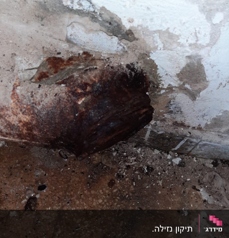 צינור חלוד עם נזילה על רצפה רטובה